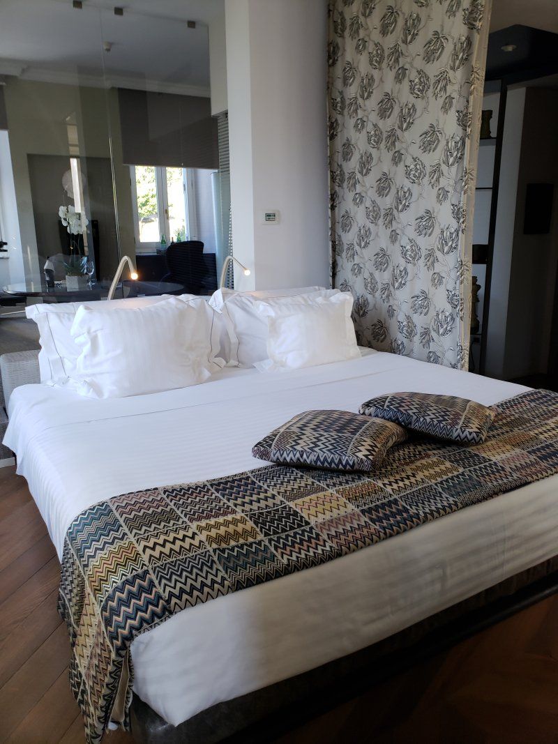 A bed with white sheets and pillows in a hotel room