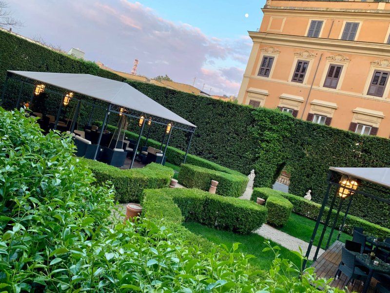 A lush green garden with a large building in the background