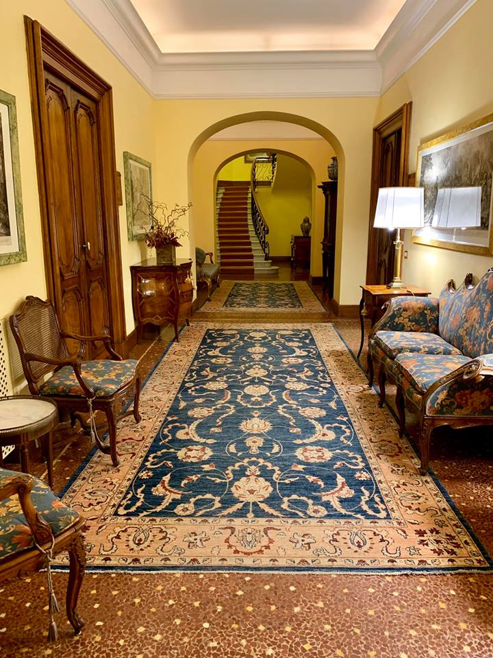 A hallway with a blue rug and a staircase in the background