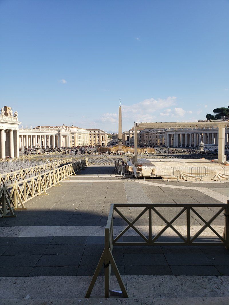 A view of a city from a balcony with a wooden fence in the foreground.