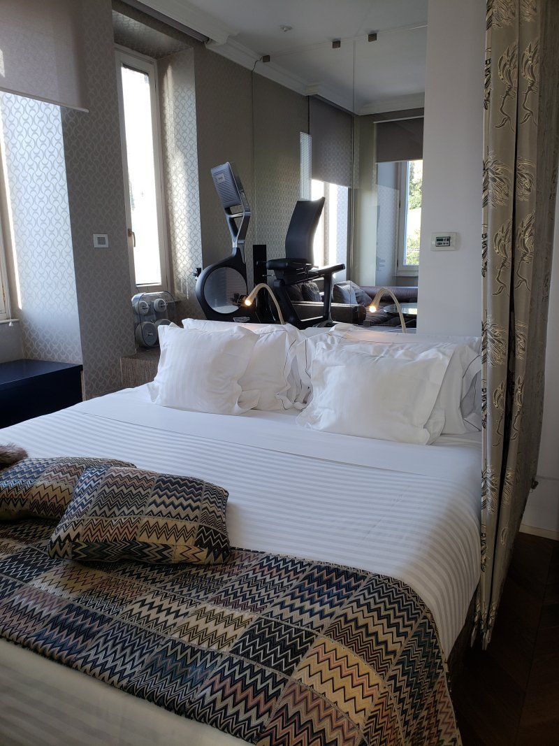 A bed with white sheets and pillows in a hotel room.
