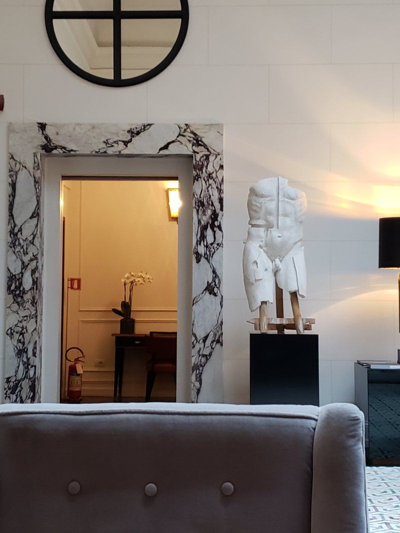 A living room with a couch and a statue on a pedestal