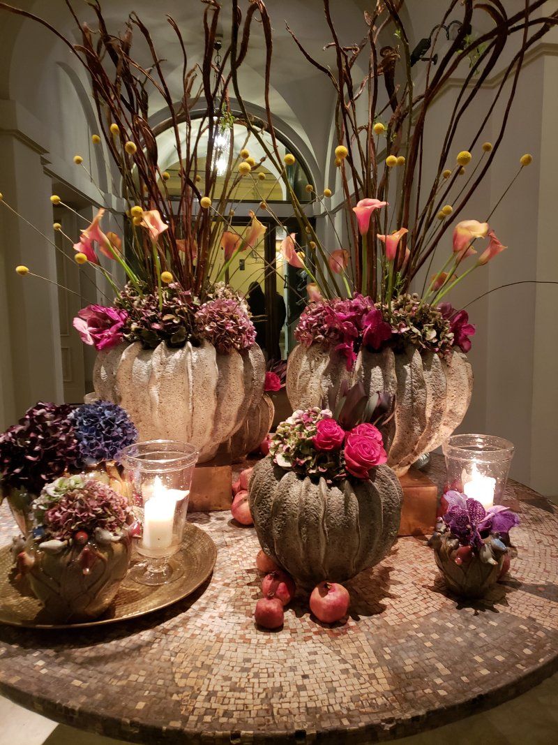A table with vases of flowers and candles on it.