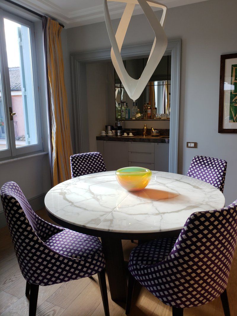 A dining room with a round table and purple chairs