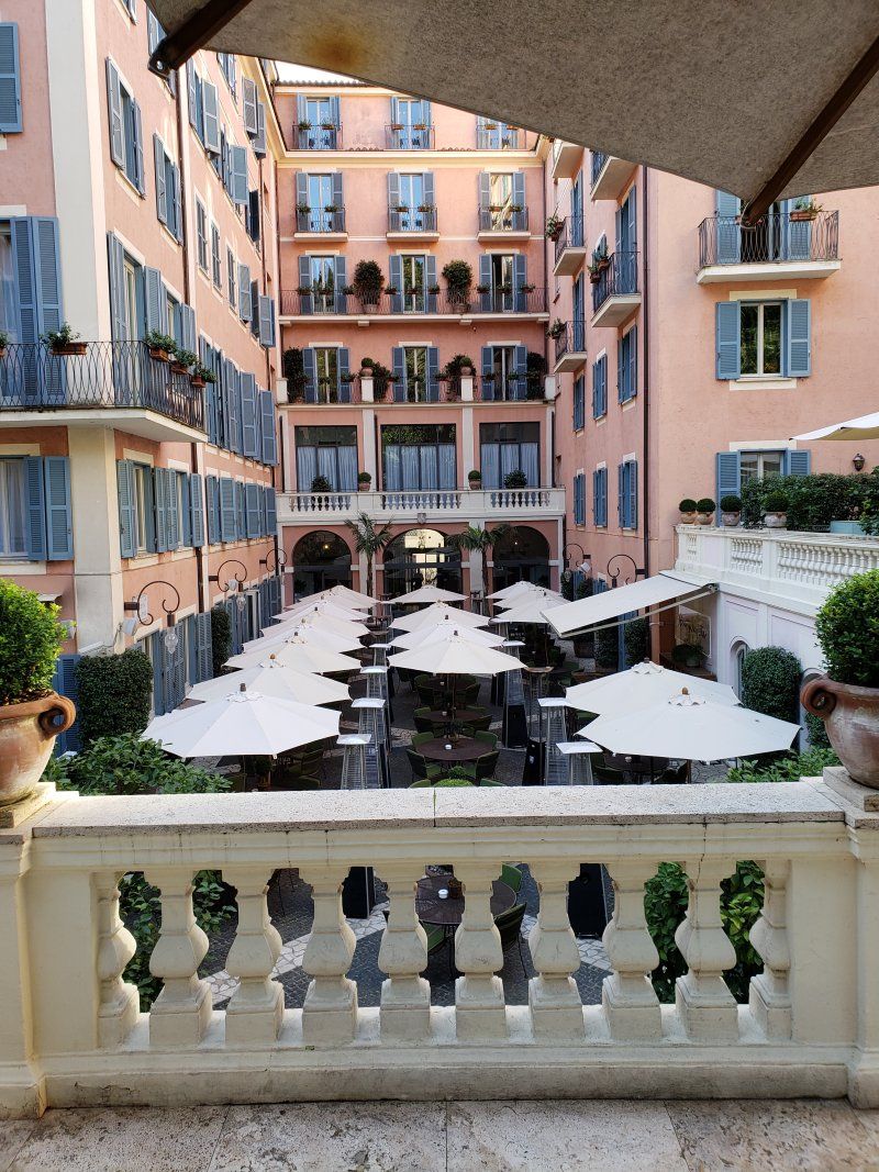 A balcony overlooking a courtyard filled with tables and umbrellas