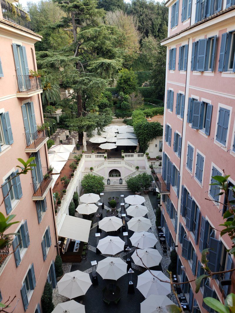 A row of umbrellas are lined up in a courtyard between two buildings.