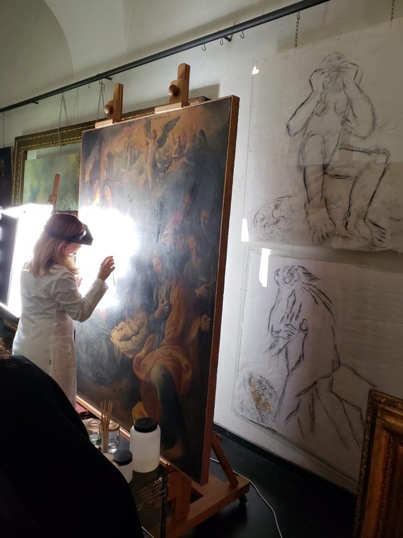 A woman is painting a large painting on an easel