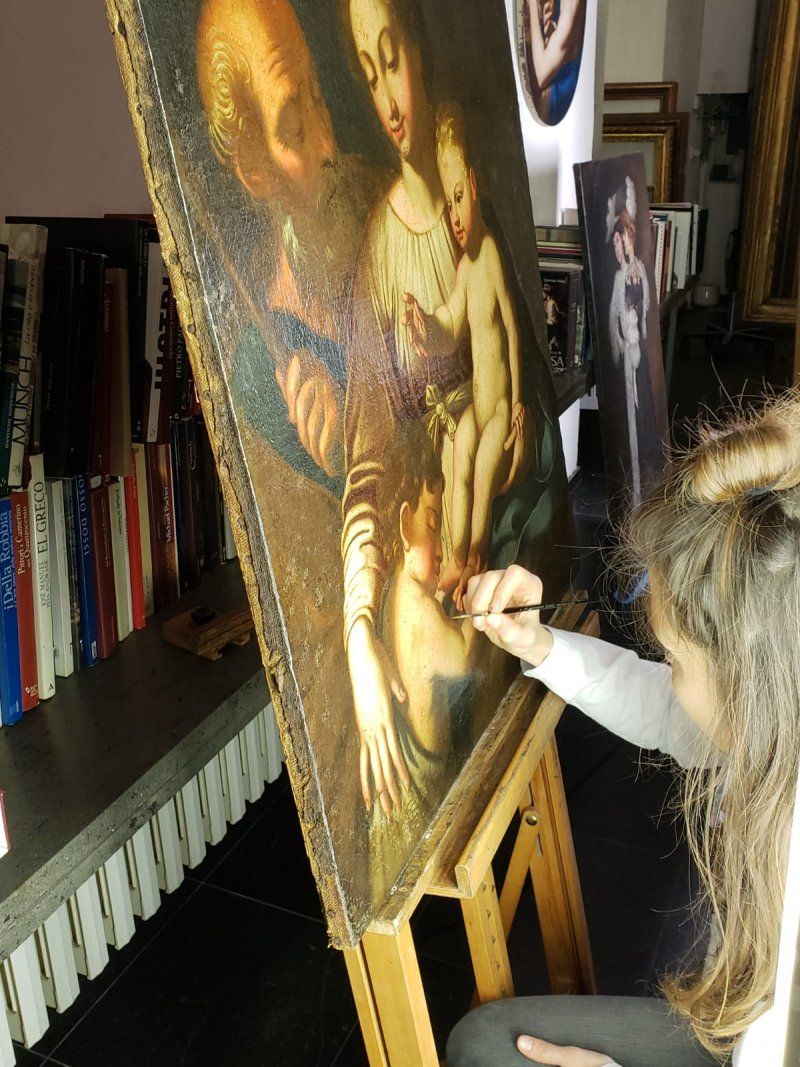 A woman is painting a picture of a woman and child on an easel.