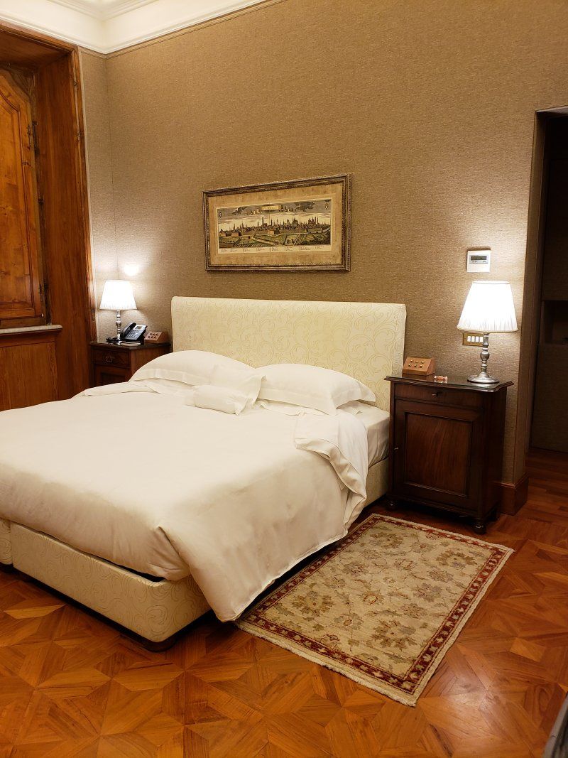 A bedroom with a large bed , nightstands , lamps and a rug on the floor.