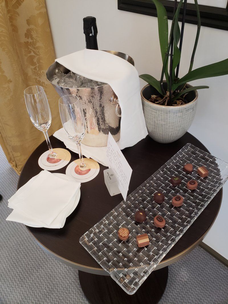 A table with a tray of chocolates and a bottle of champagne