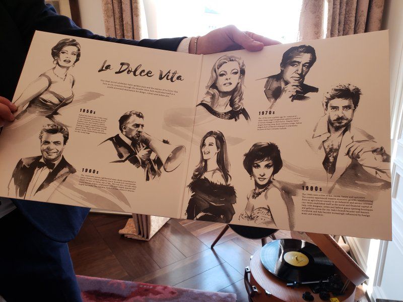 A man is holding a book that says la dolce vita