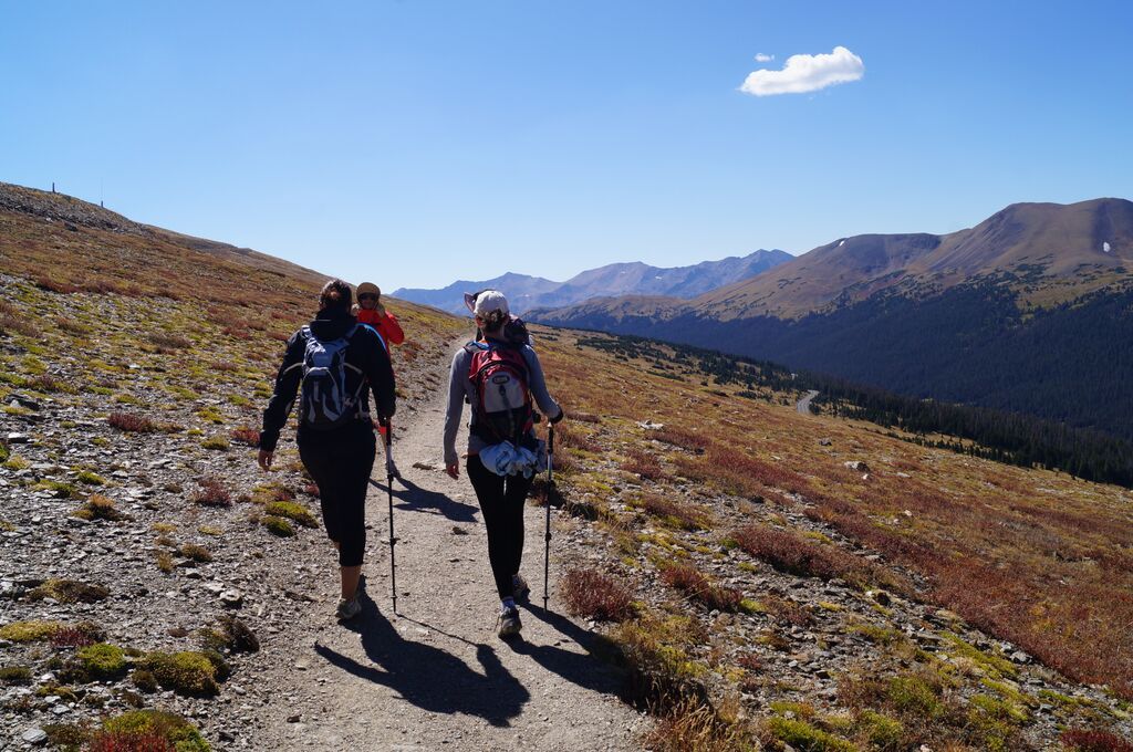 A group of people are walking down a dirt path in the mountains.