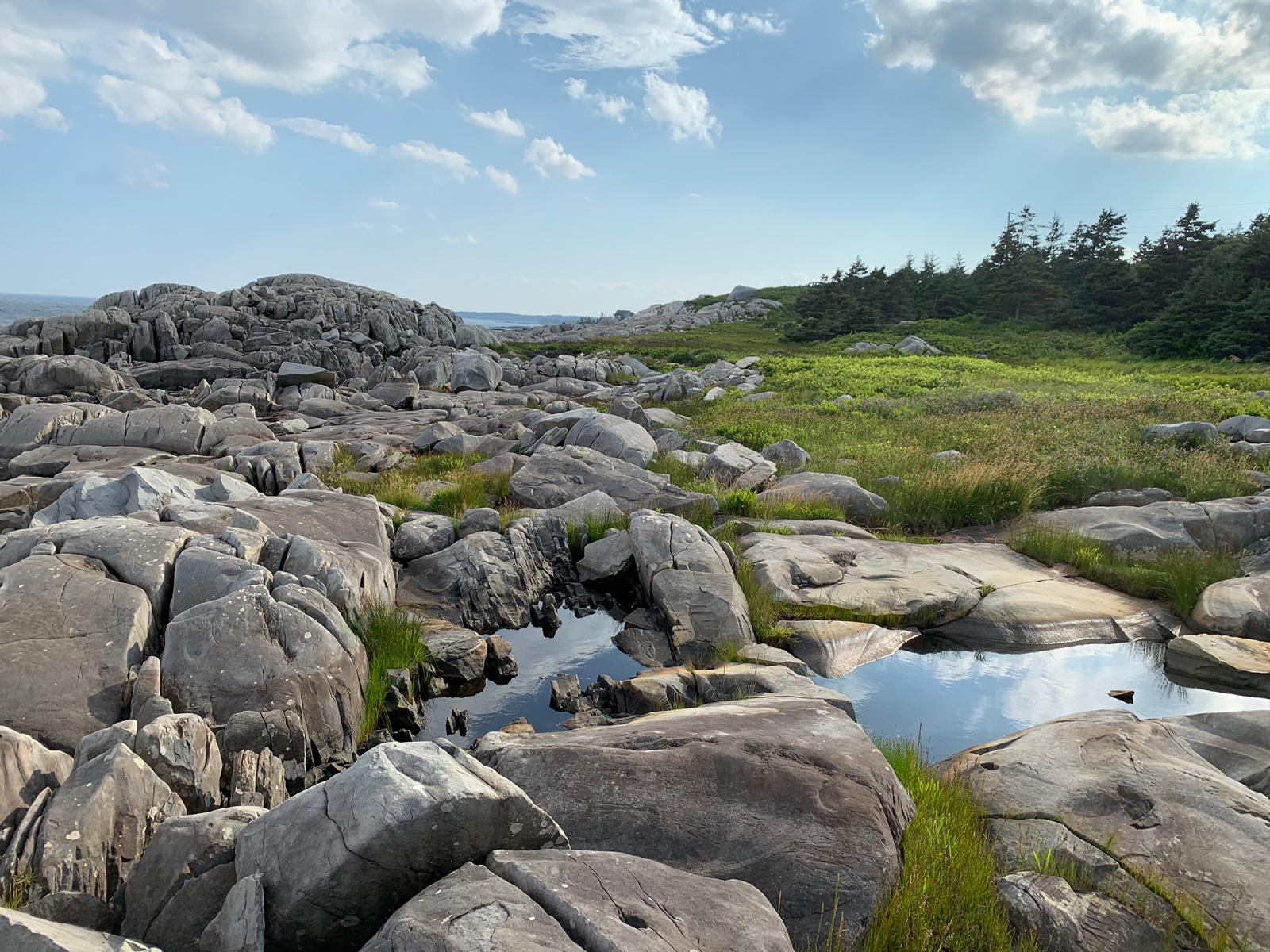 A landscape of rocks and grass with a body of water in the middle