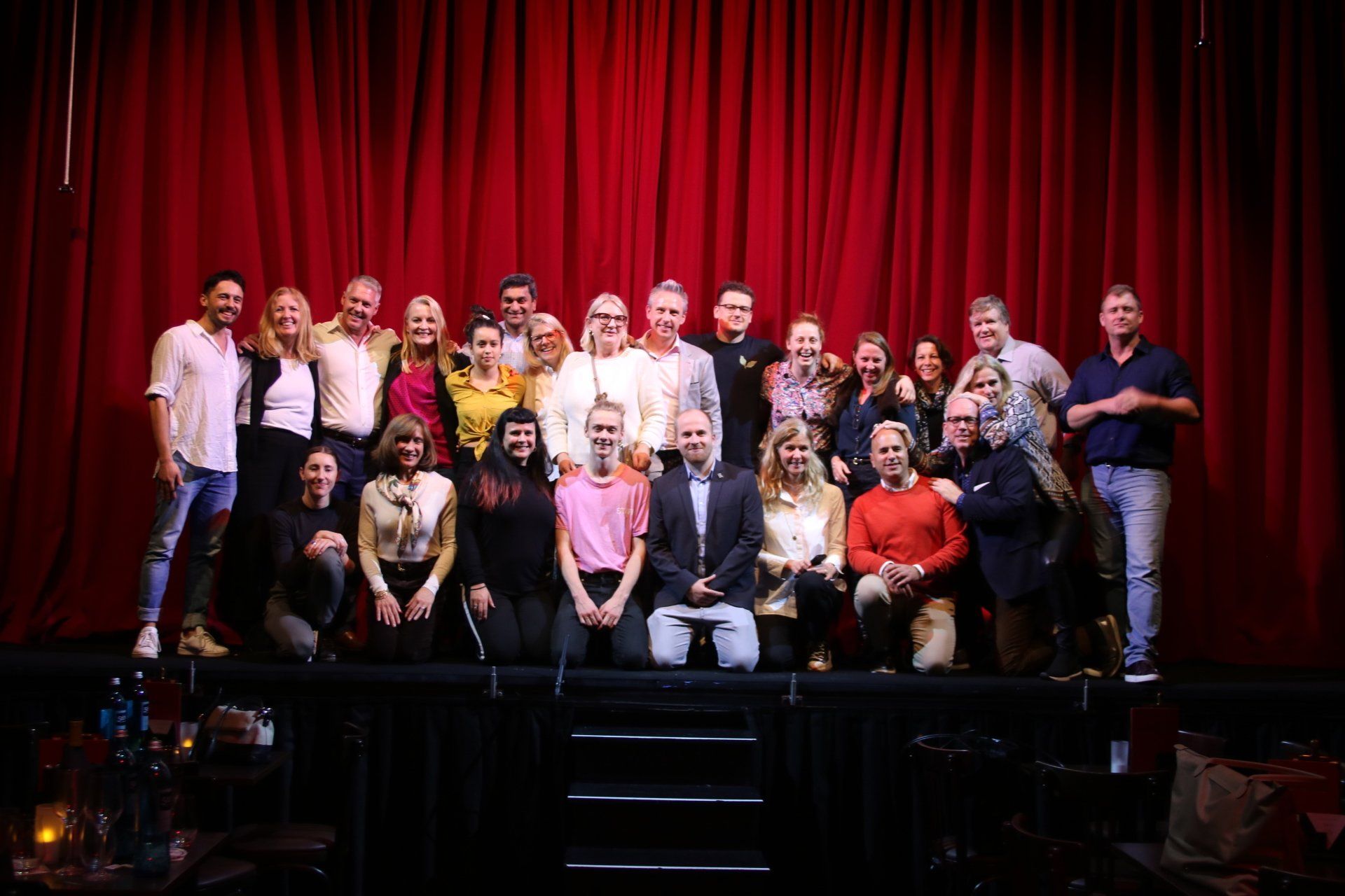A large group of people are posing for a picture on a stage.