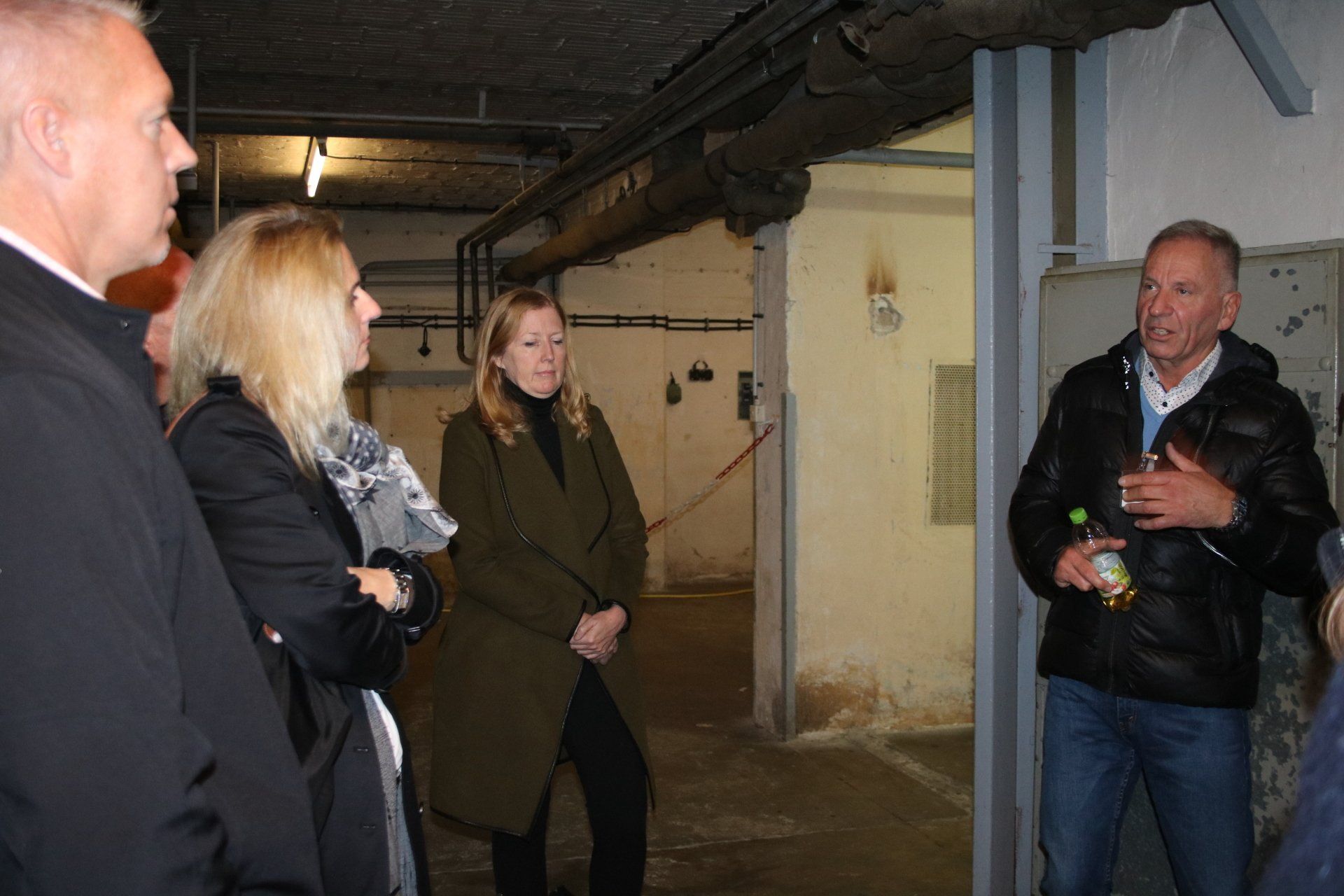A group of people are standing in a room talking to each other.