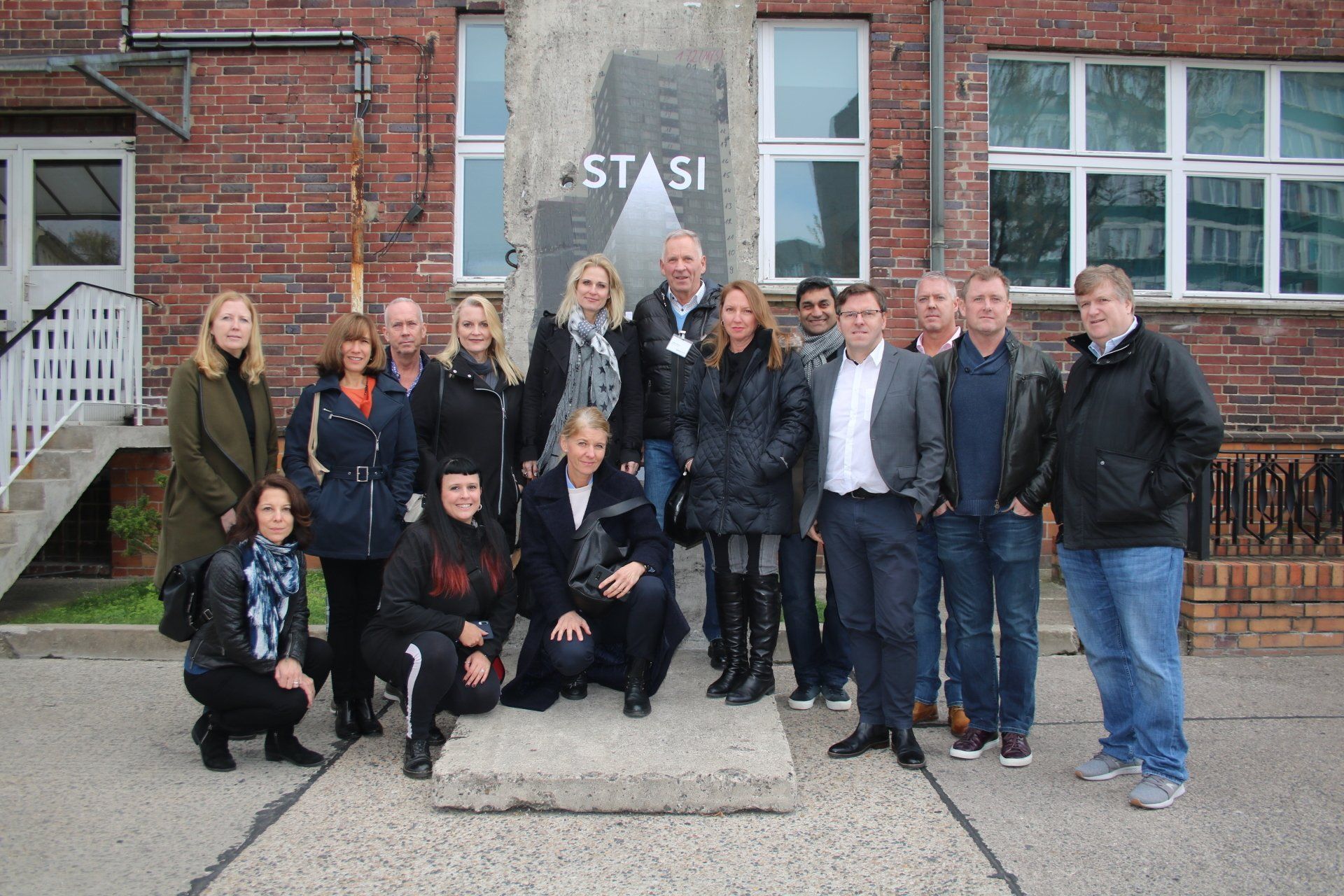 A group of people are posing for a picture in front of a brick building.
