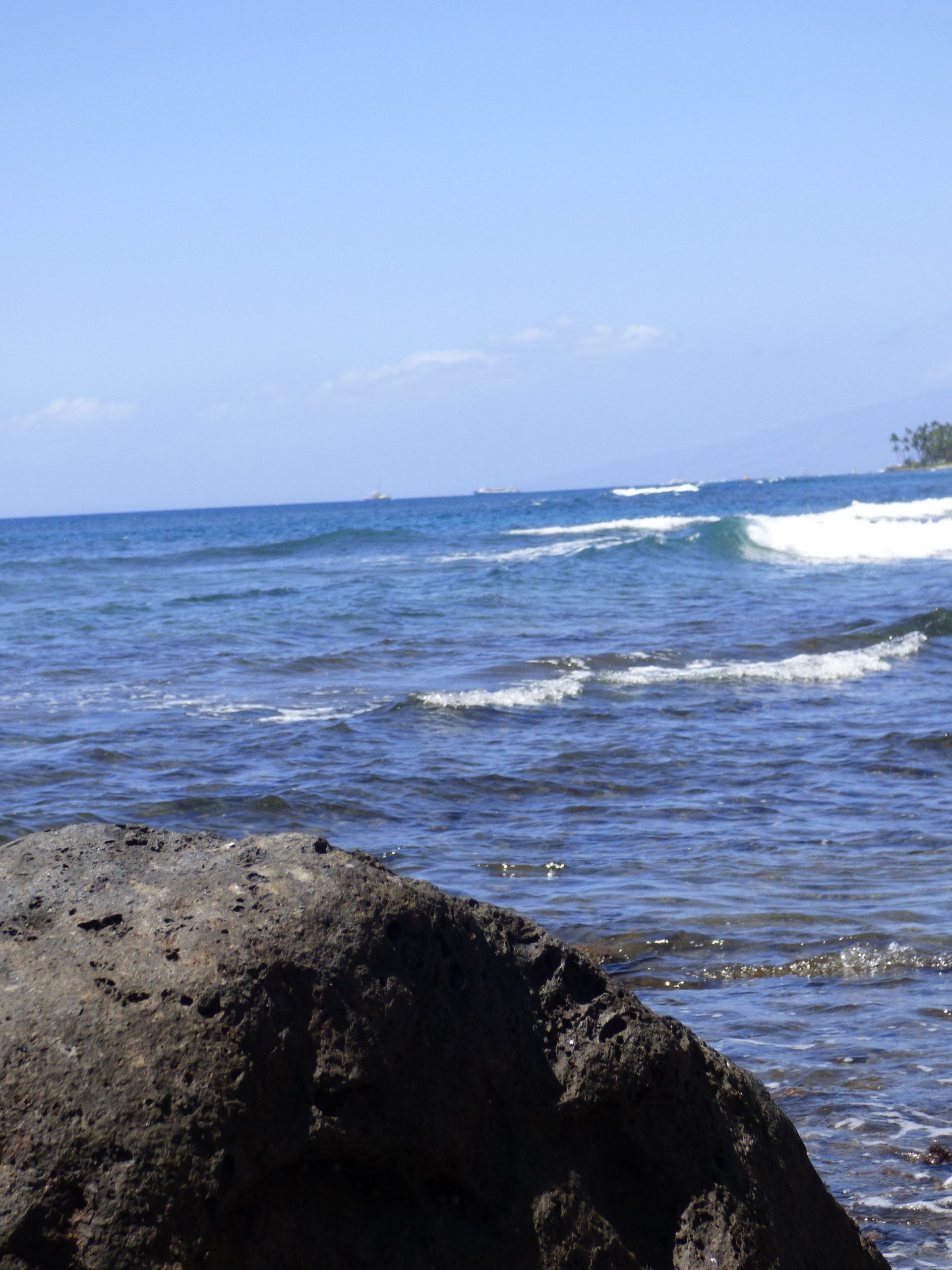 A large rock sits on the beach near the ocean