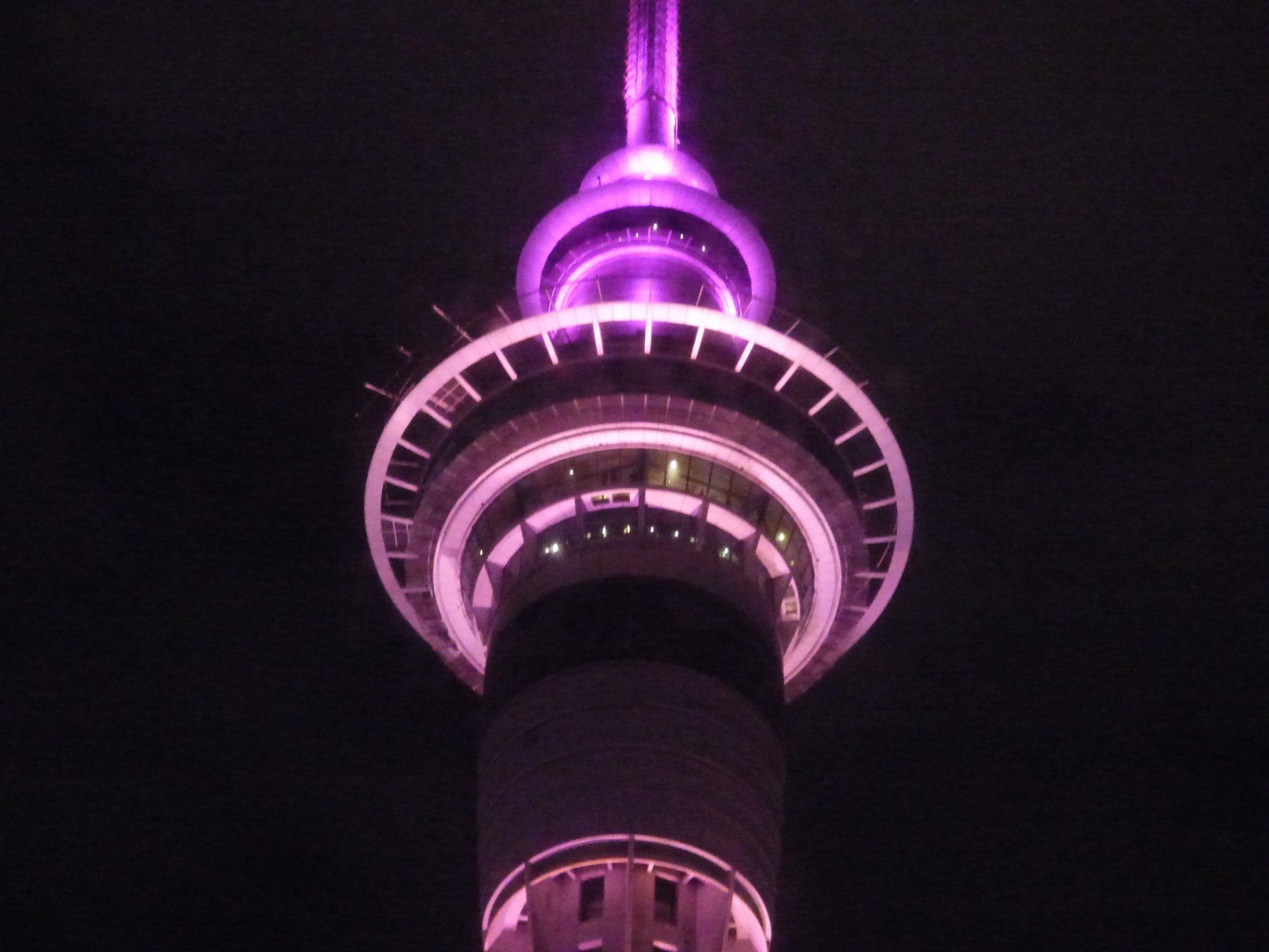 A purple lighted tower is lit up at night