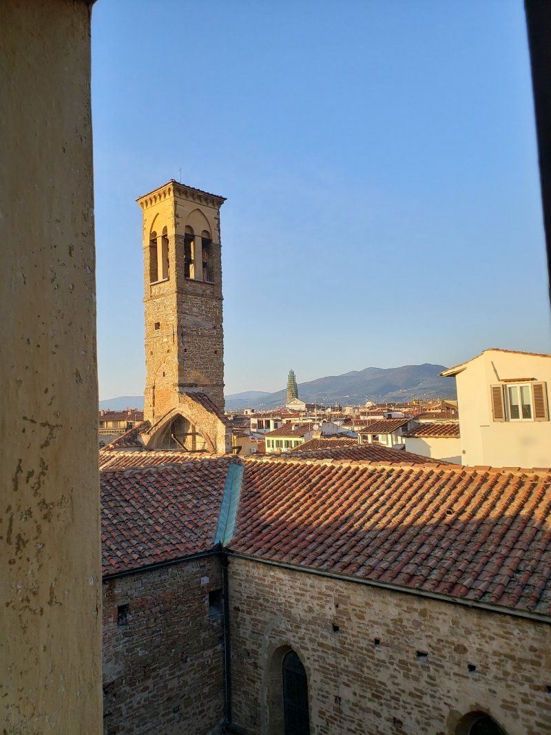 A view of a city from a balcony with a clock tower in the background.