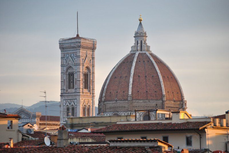 A dome with a clock tower in the background in a city