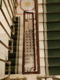 A staircase with green carpets and a wooden railing.