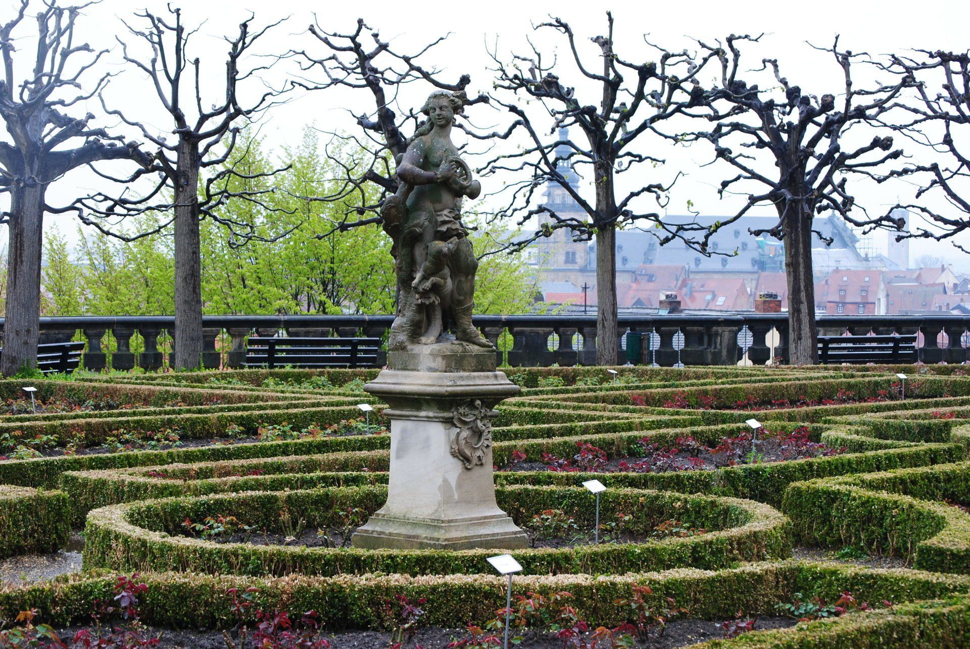 A statue in the middle of a maze in a garden