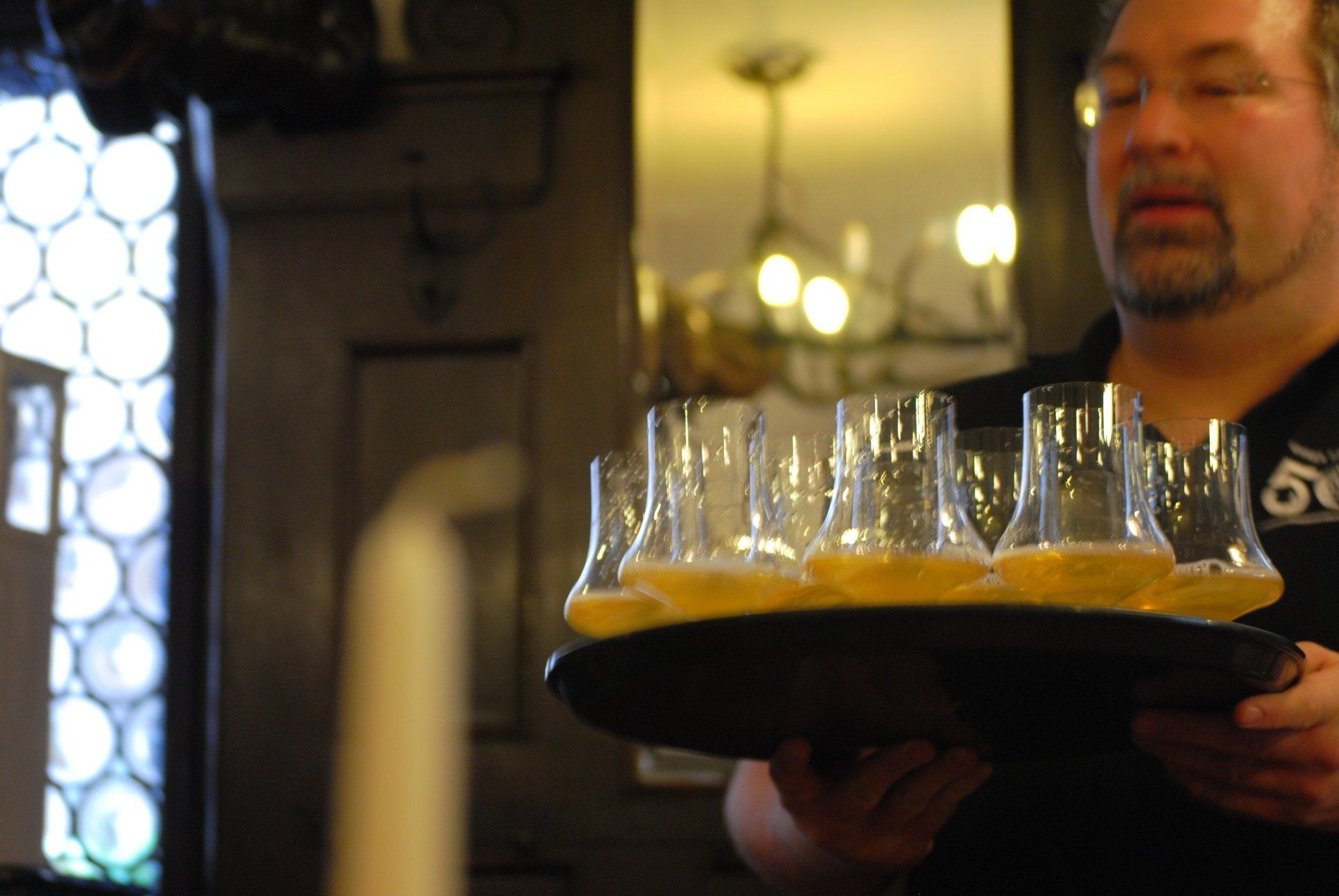 A man is holding a tray of glasses of beer