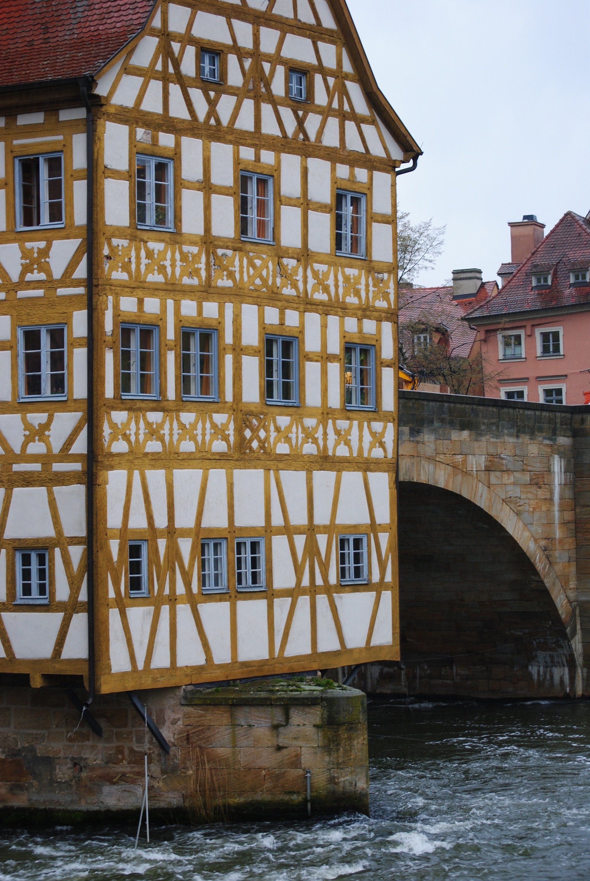 A half timbered building is next to a bridge over a river