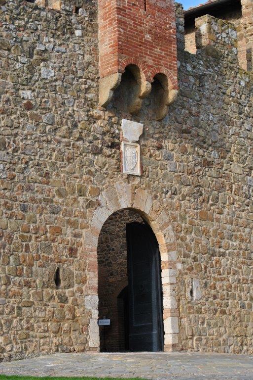 A stone wall with a door and a brick chimney on top of it.
