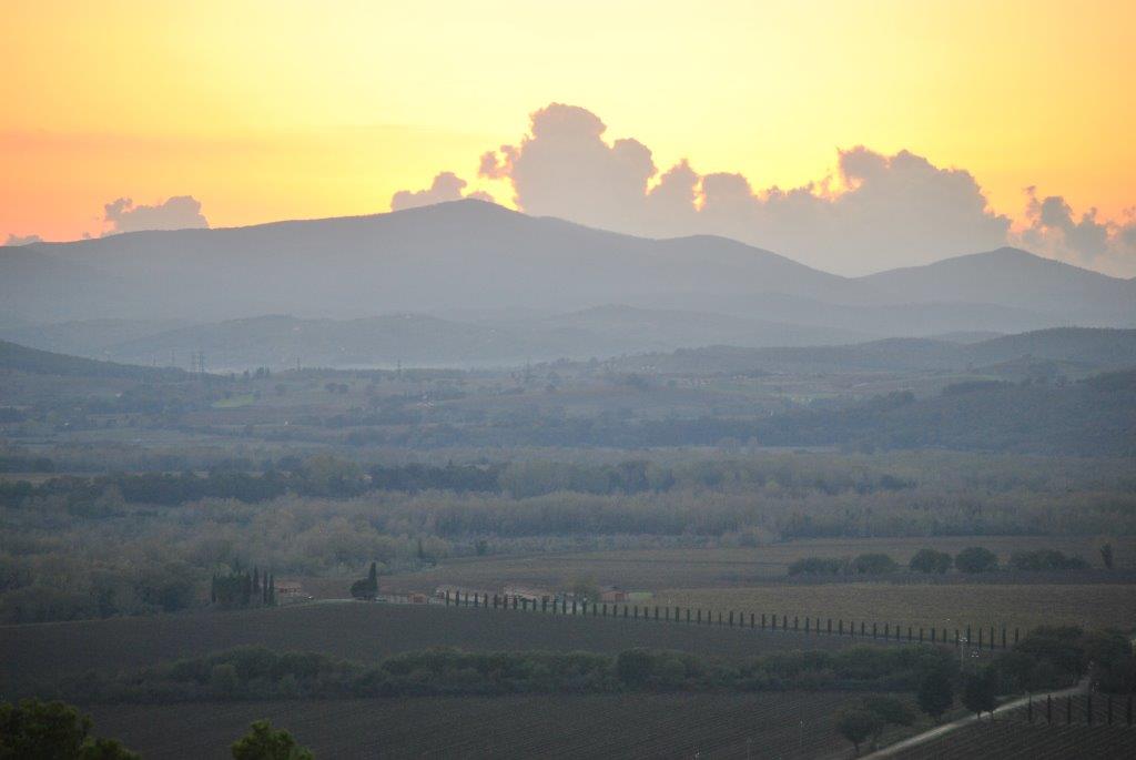 A sunset over a valley with mountains in the background.