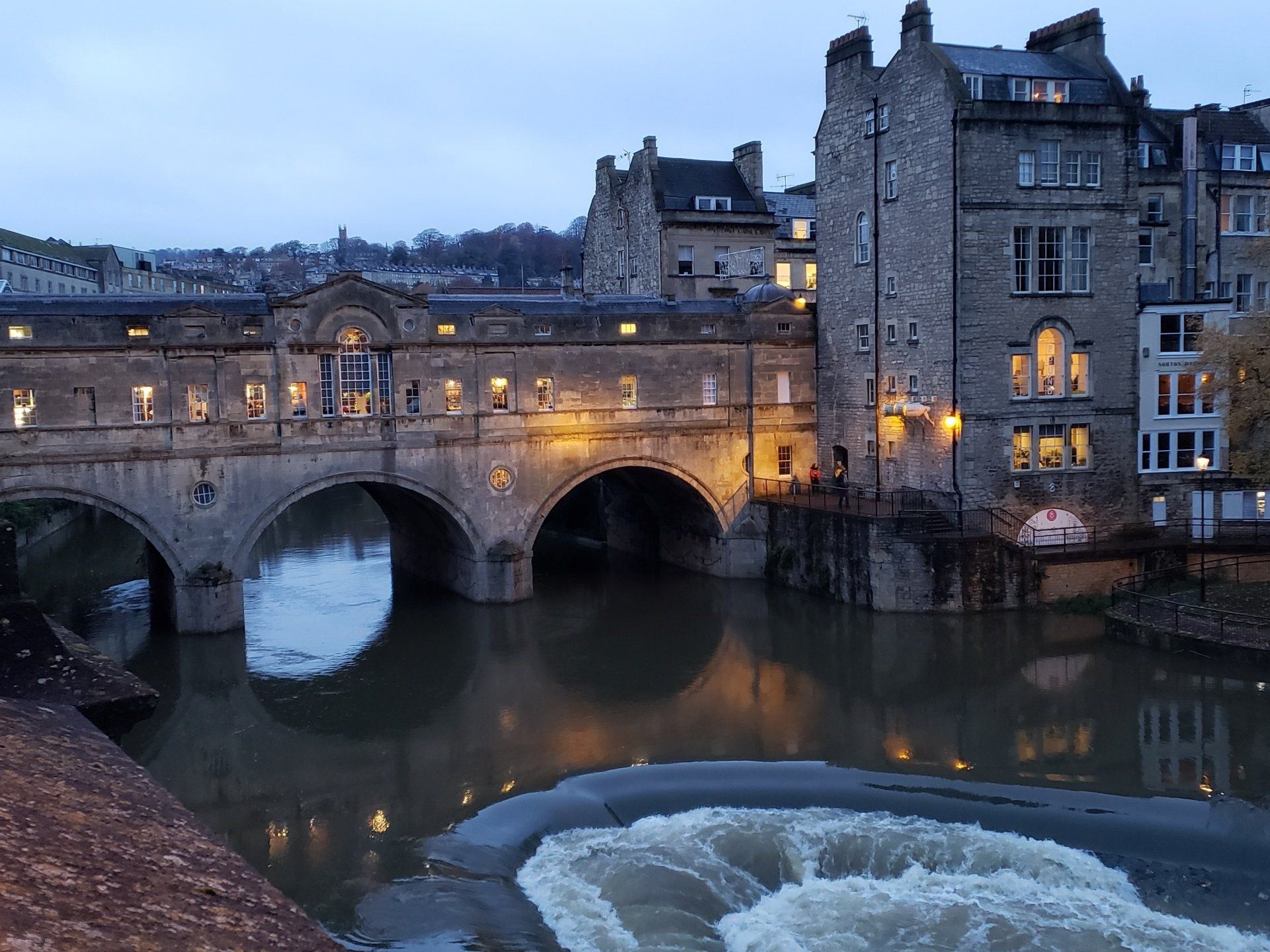 A bridge over a river in a city with buildings in the background.