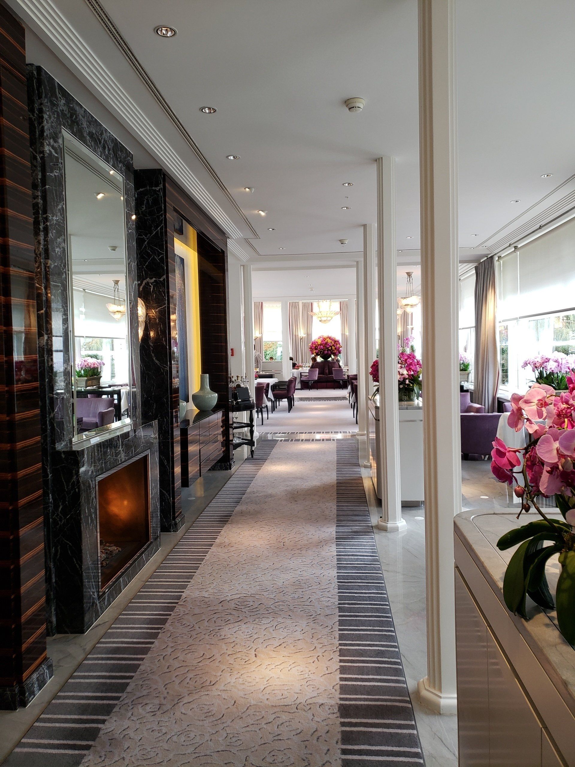 A long hallway in a hotel with a fireplace and flowers