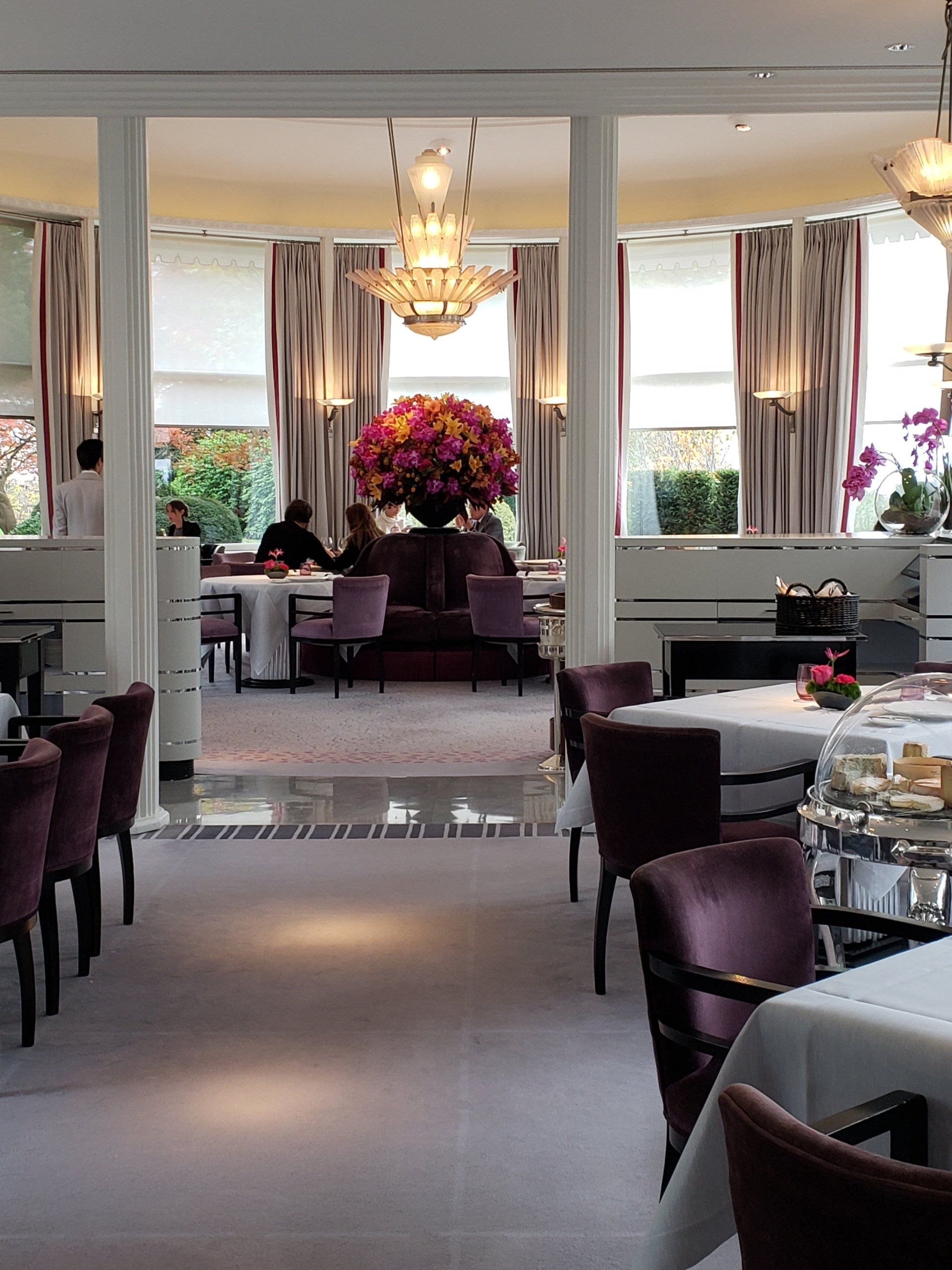 A restaurant with tables and chairs and a vase of flowers in the middle