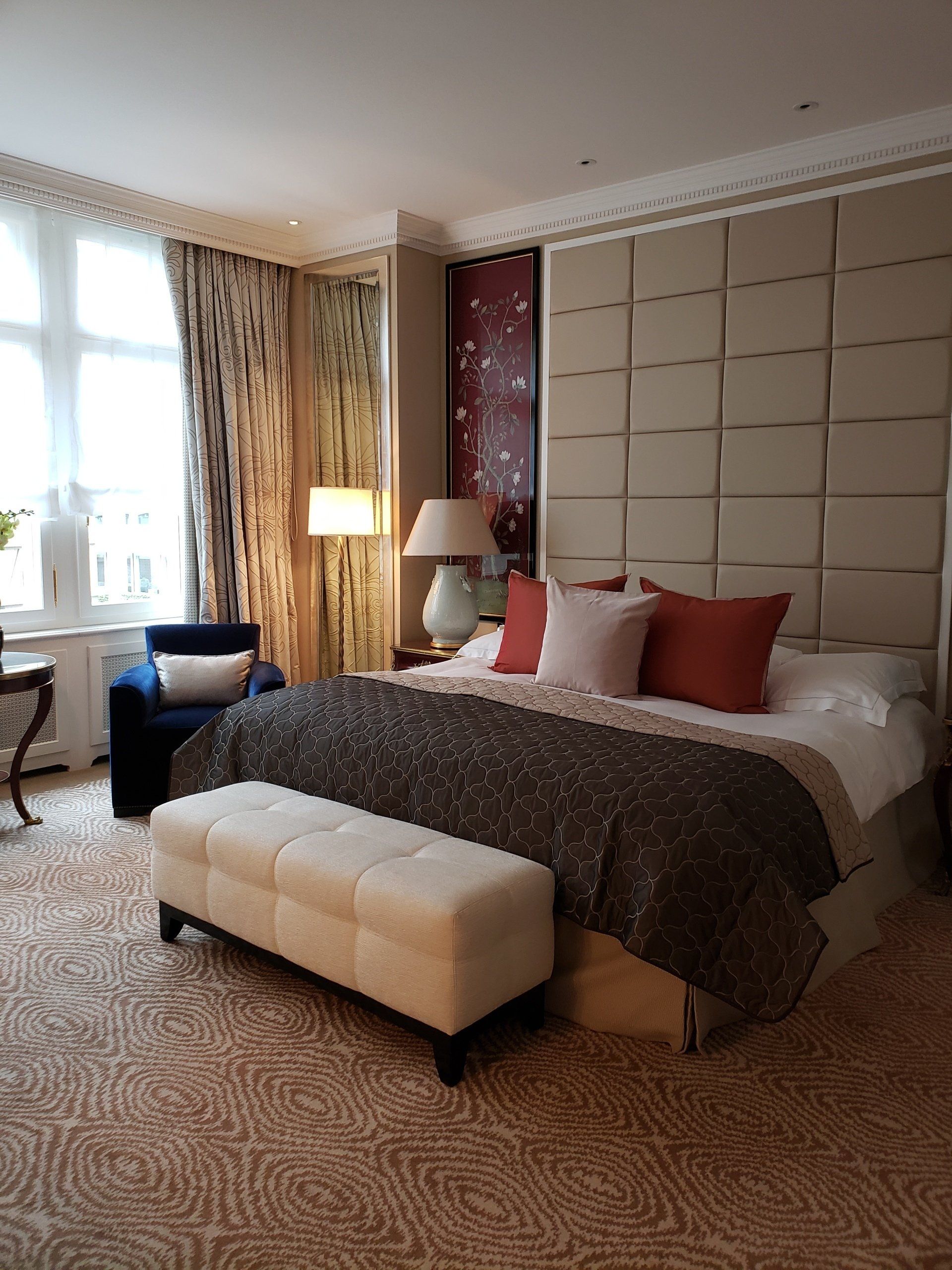 A hotel room with a large bed and a bench