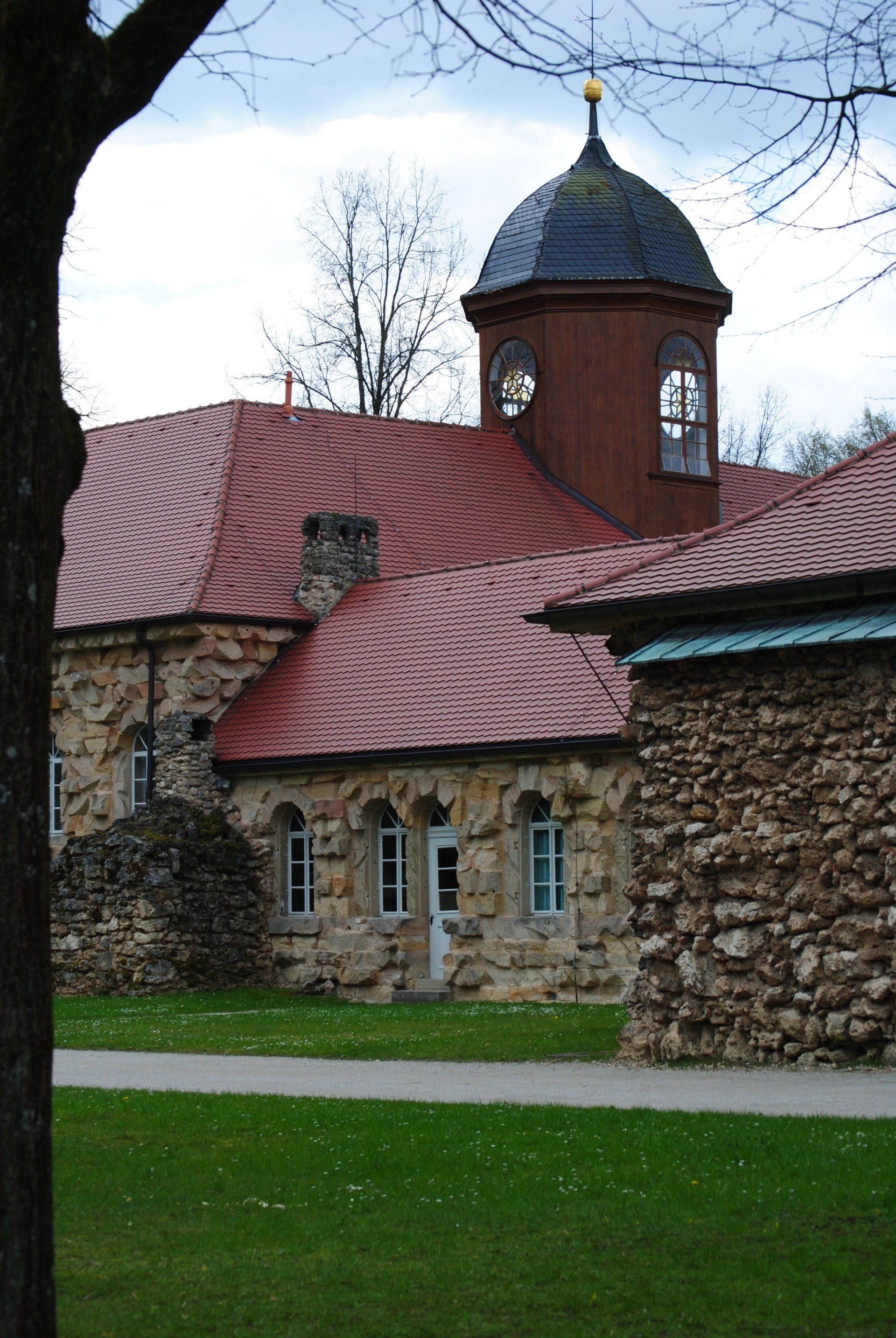A stone building with a red roof and a clock tower