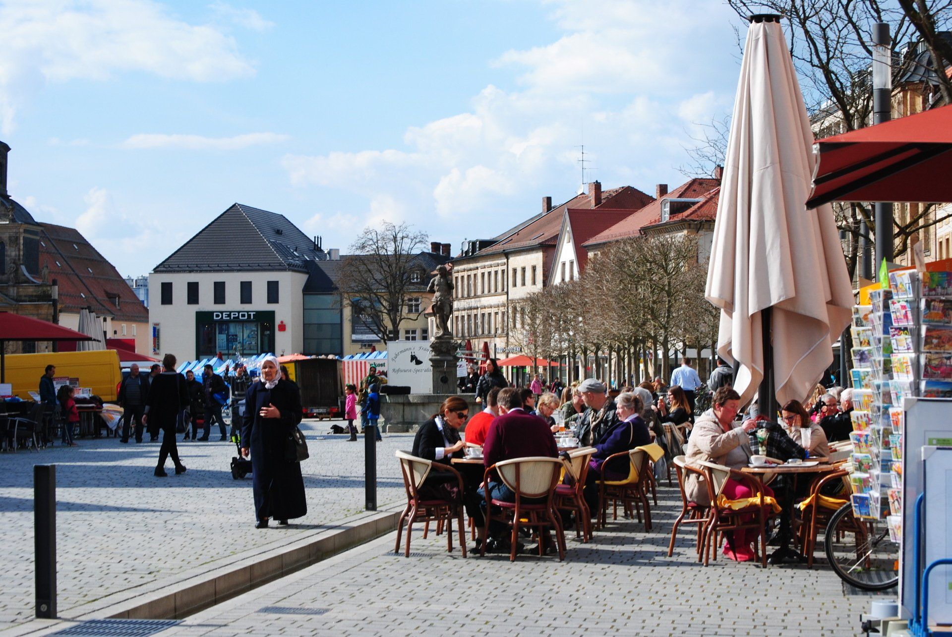 A group of people are sitting at tables outside in a city