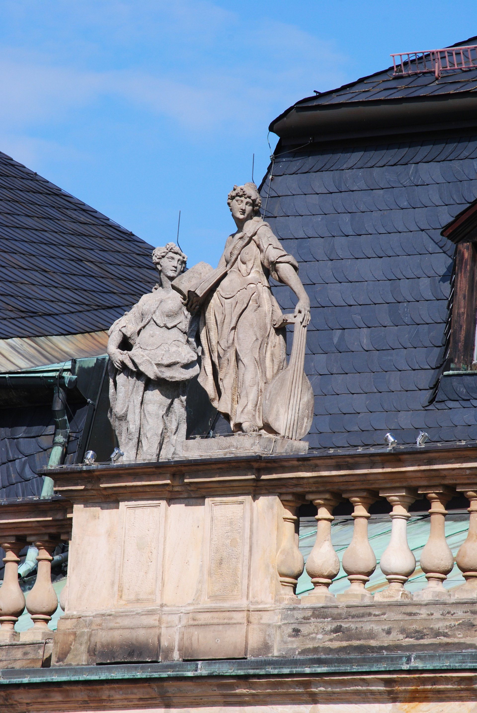 Two statues on top of a building with a slate roof