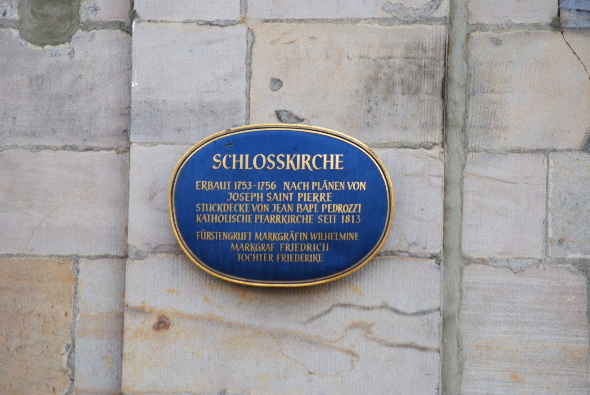 A plaque on a brick wall that says schlosskirche