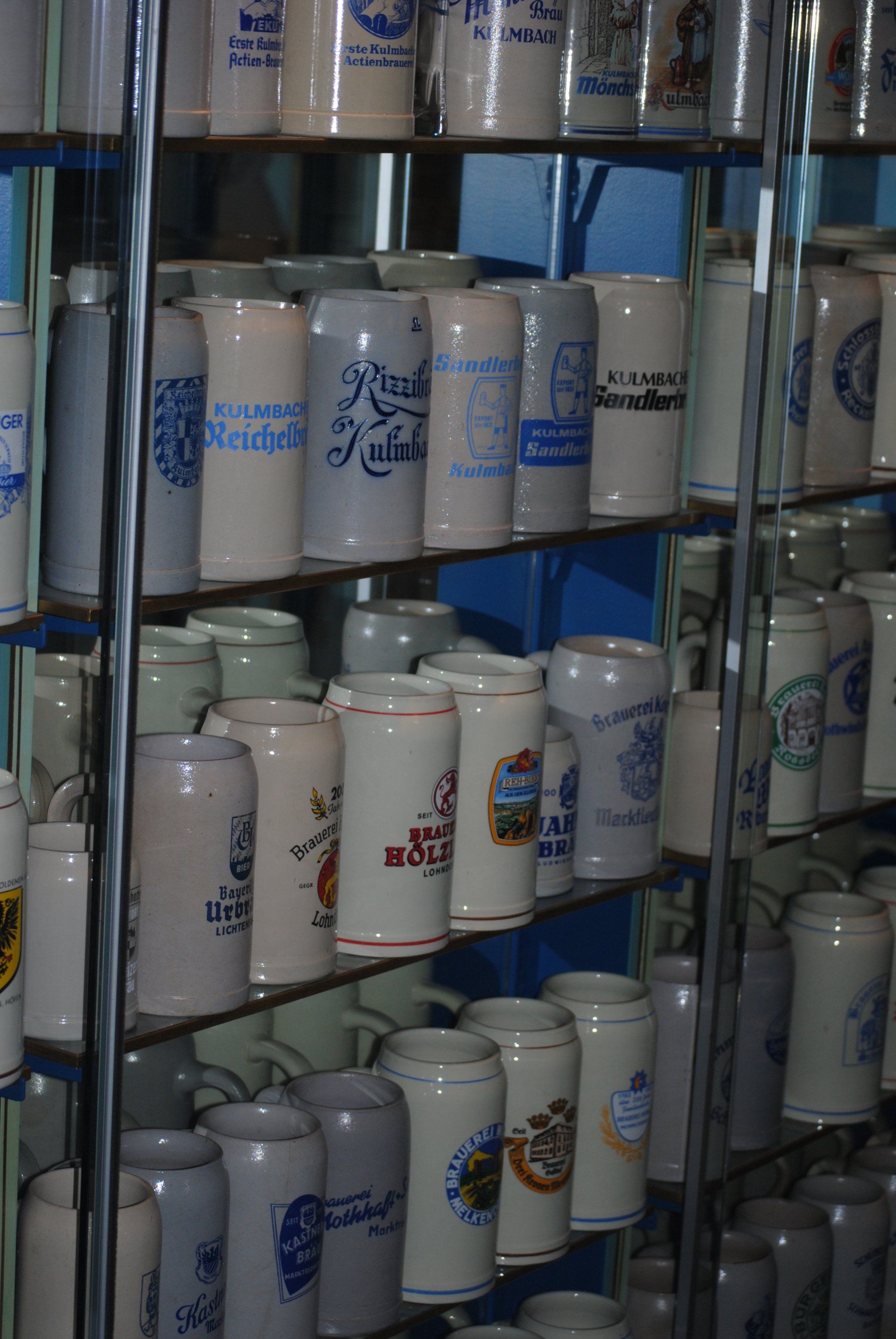 A shelf filled with many different types of beer mugs