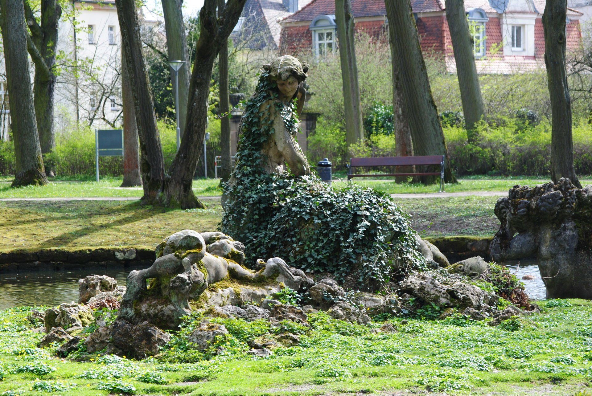 A statue of a woman surrounded by trees in a park