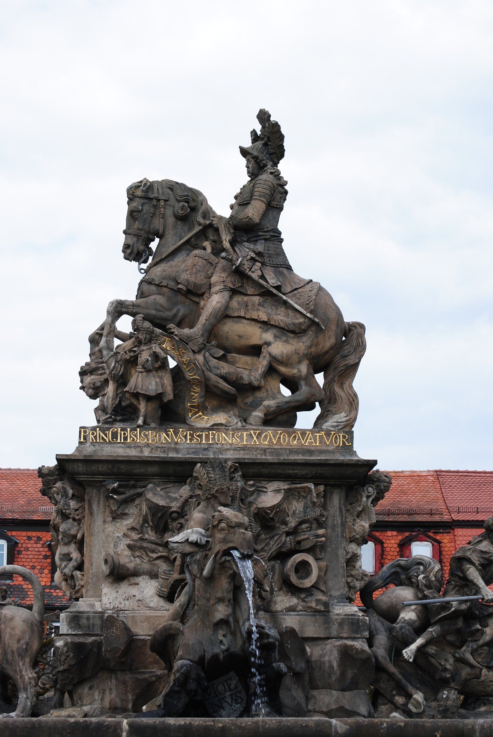 A statue of a man riding a horse in front of a fountain.