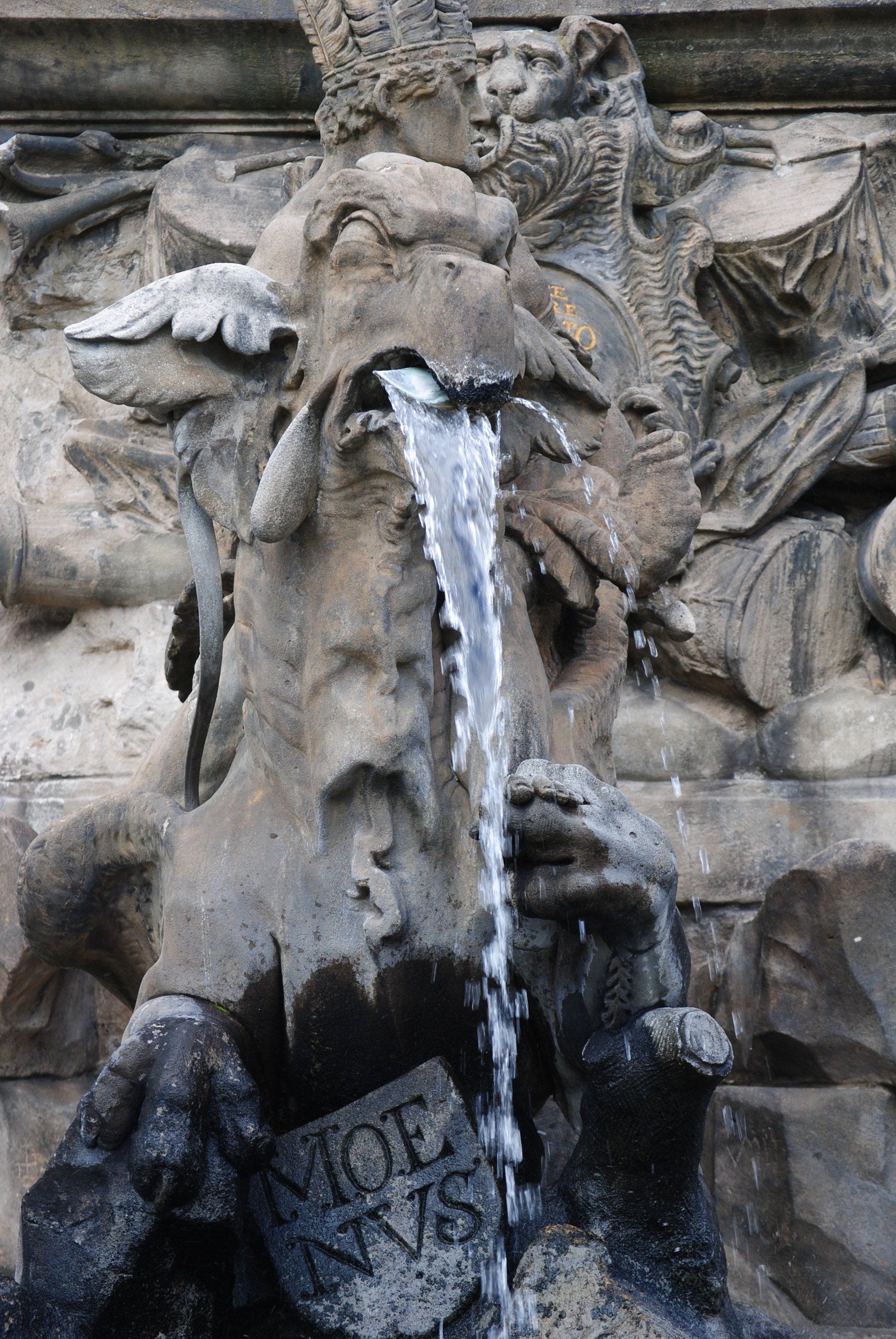 A statue of a dragon with water pouring out of its mouth.