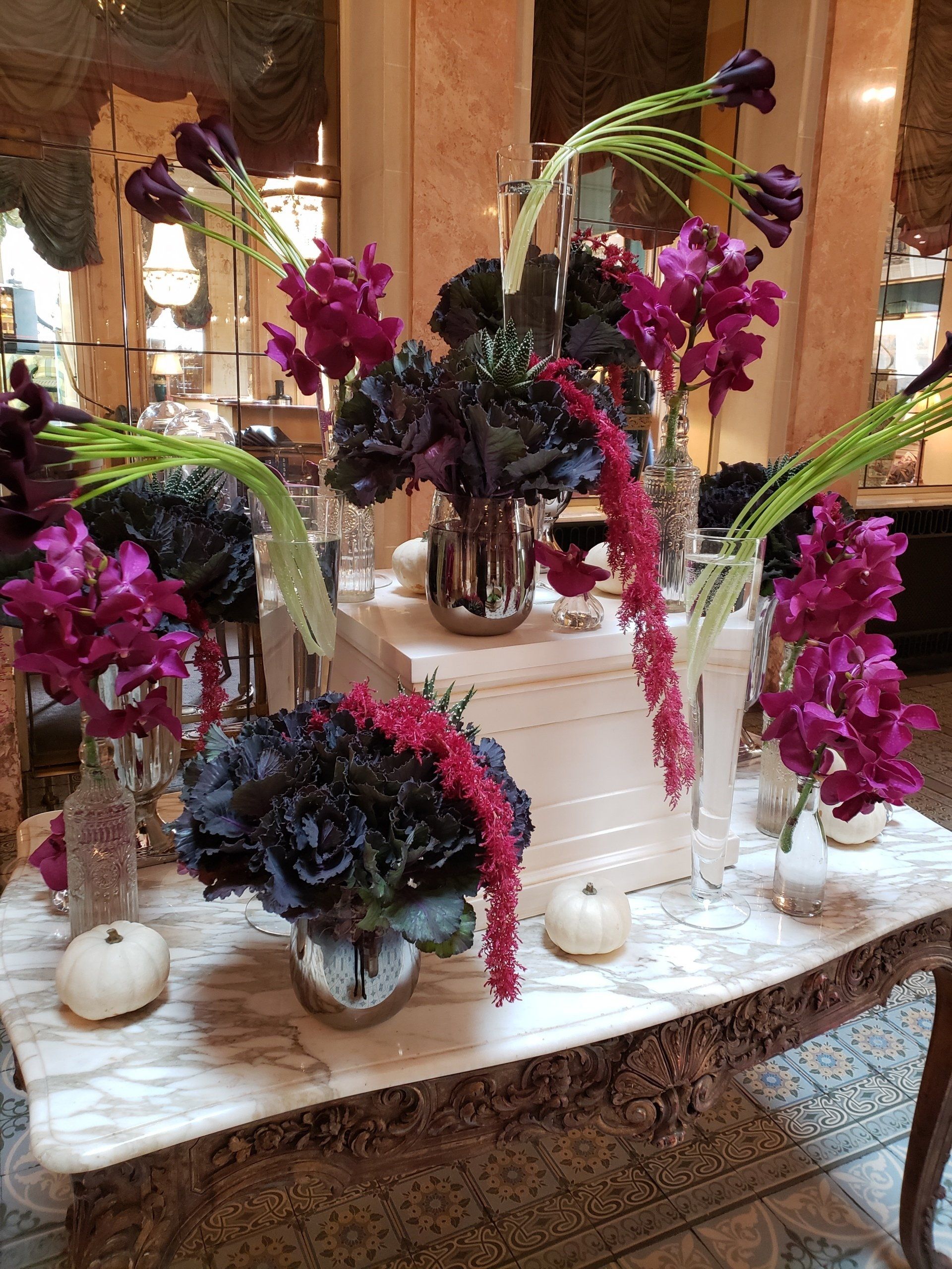 A table topped with vases of flowers and pumpkins.