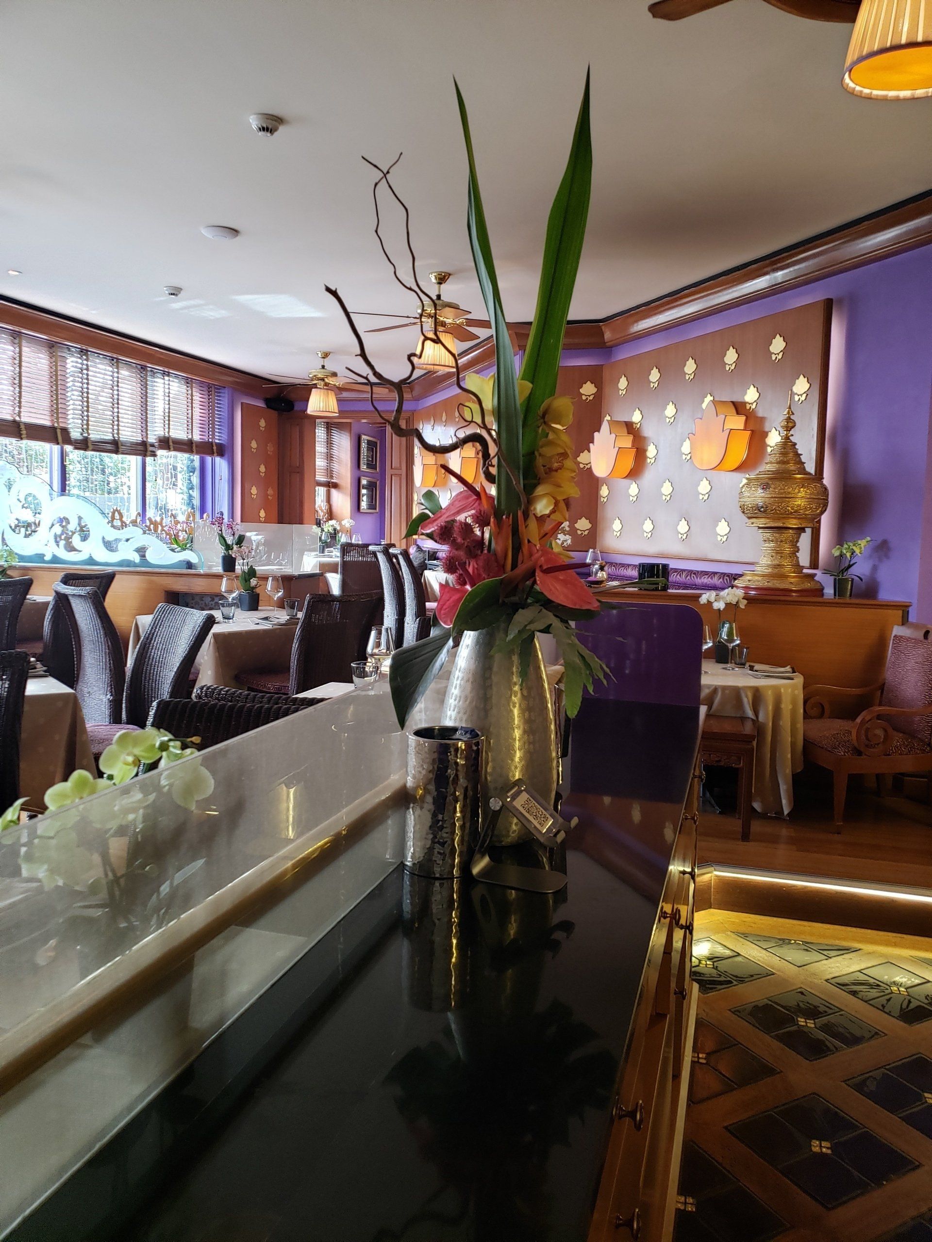 A vase of flowers sits on a table in a restaurant