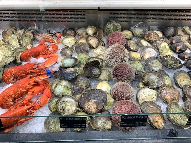 A display case filled with seafood including lobsters , clams and sea urchins.