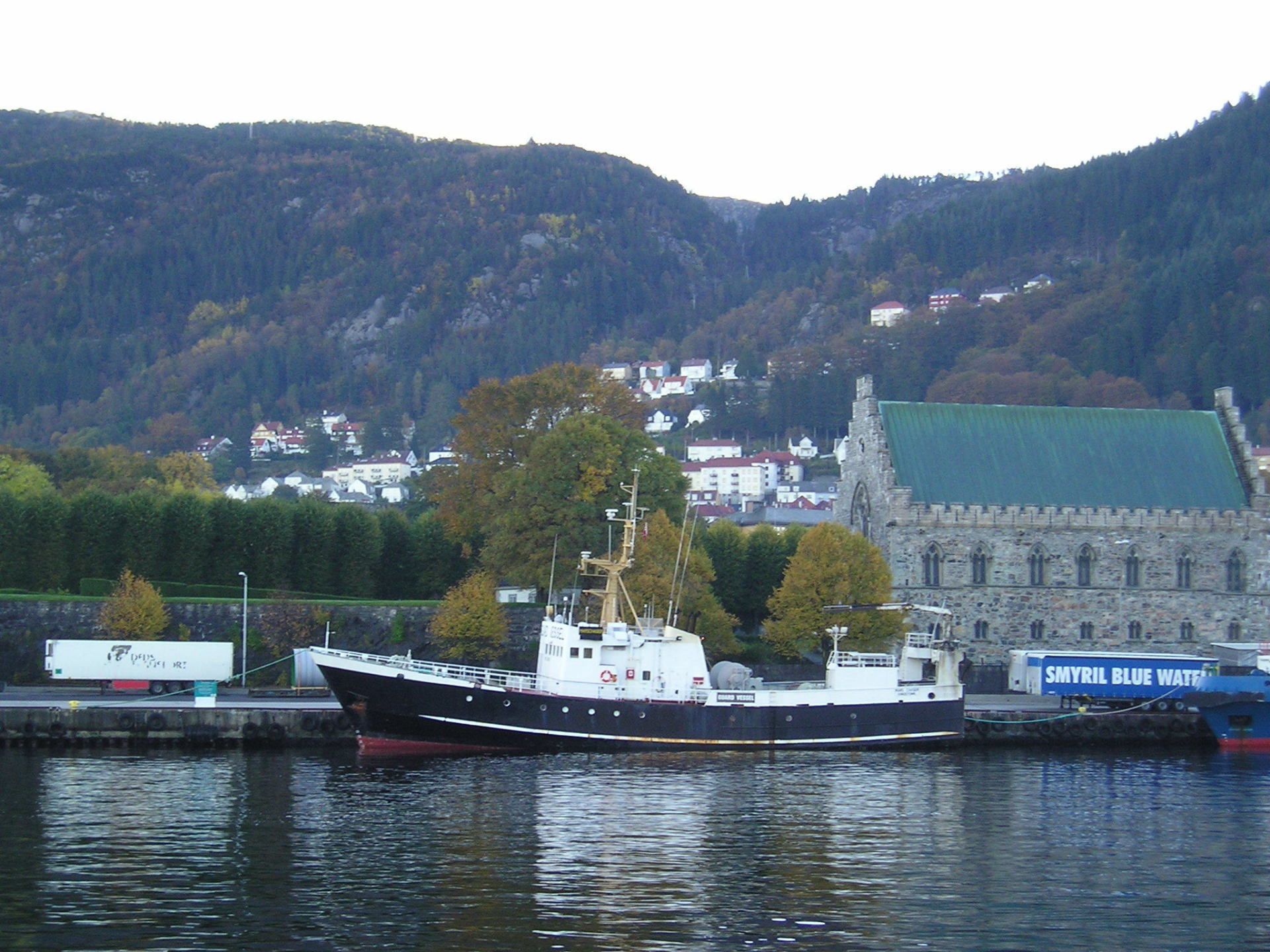 A large ship is docked in front of a building with a green roof