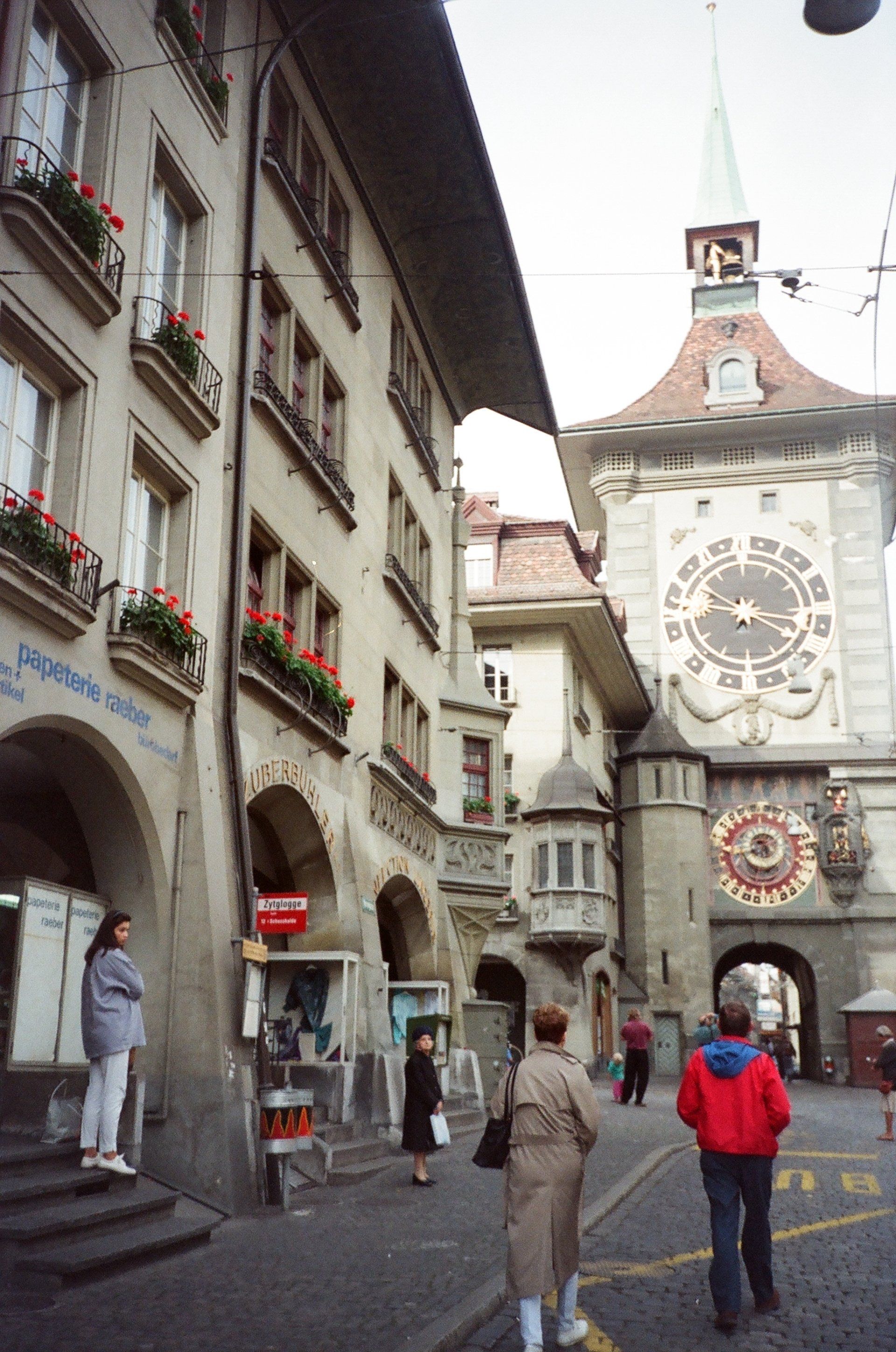 People walking in front of a building with a clock on it