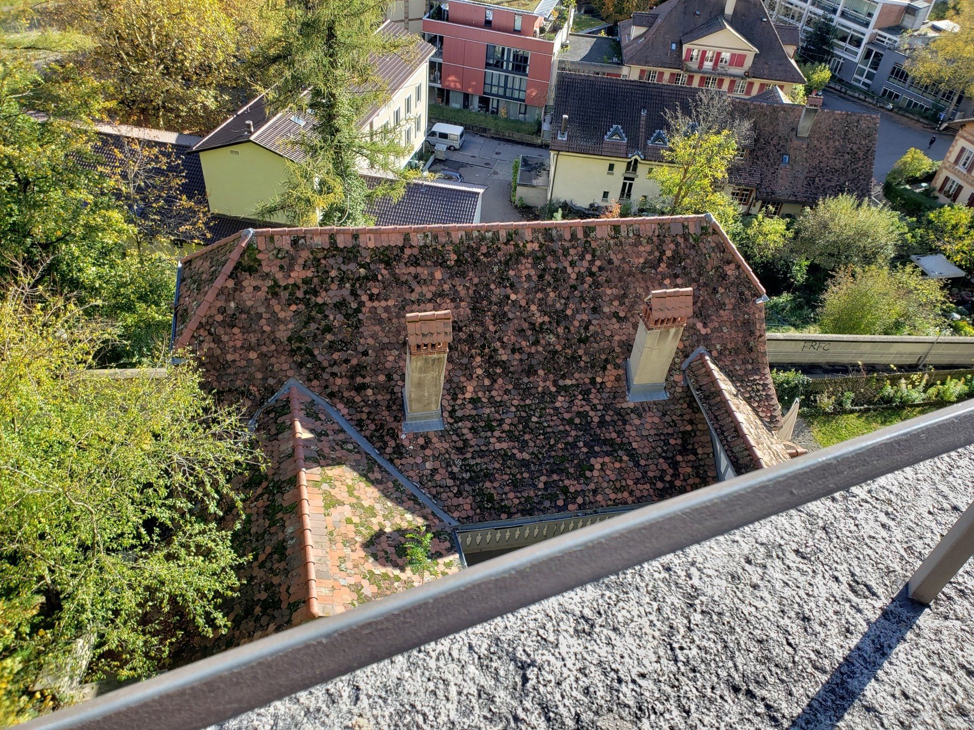 An aerial view of a brick building surrounded by trees and houses.