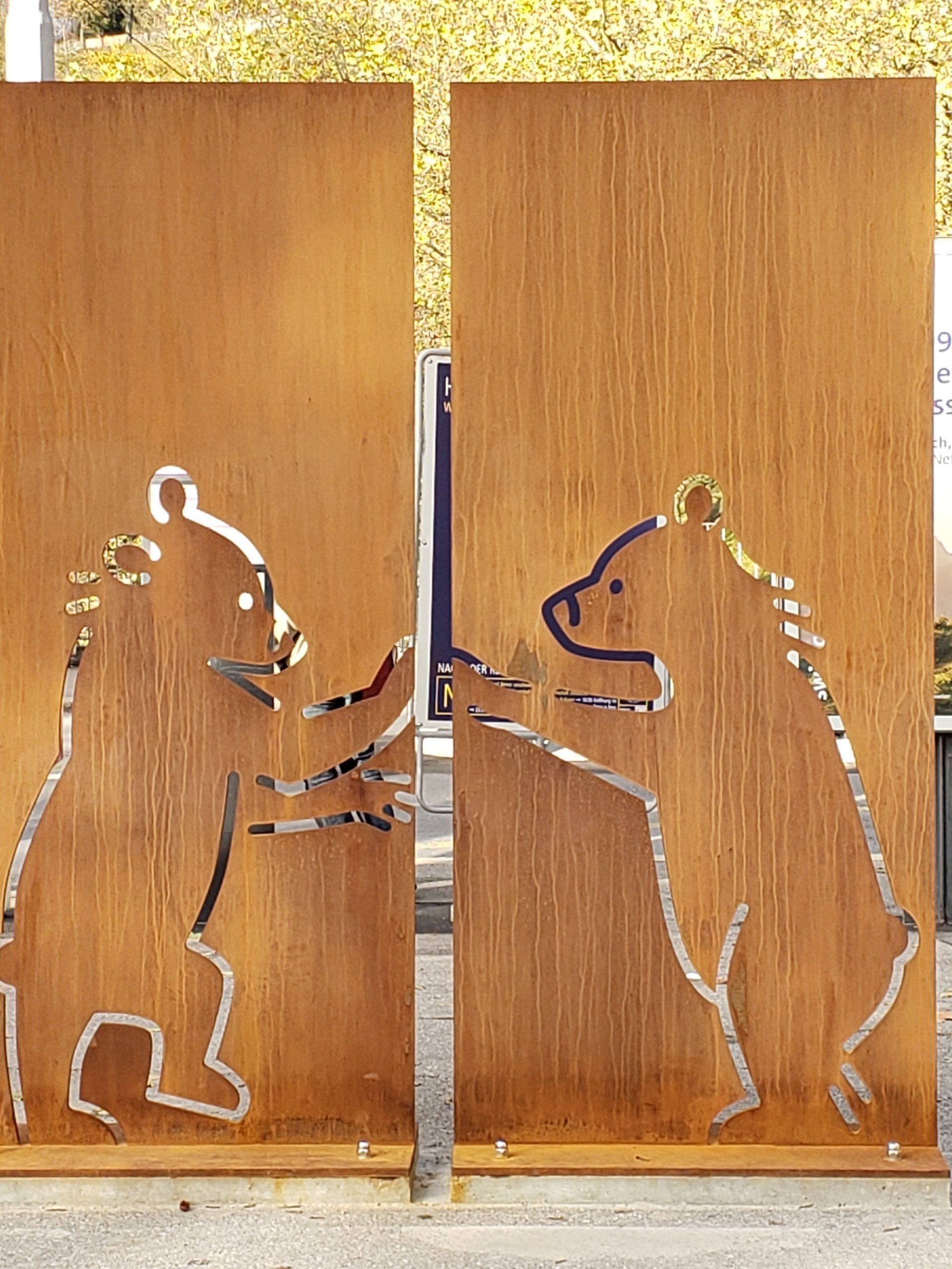 Two bears are standing next to each other on a wooden wall.