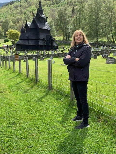 A woman is standing in a grassy field in front of a black church.